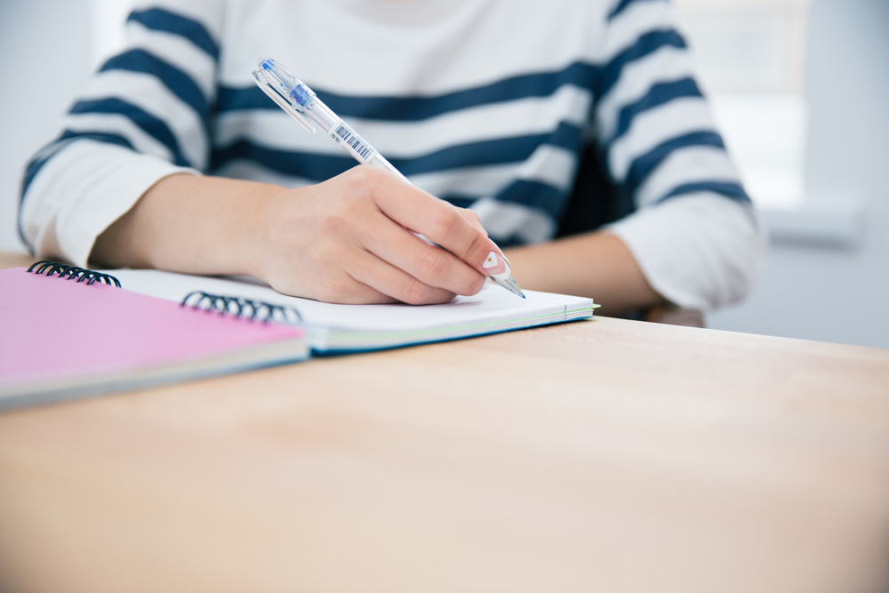 CLoseup portrait of a woman writing in notepad at office