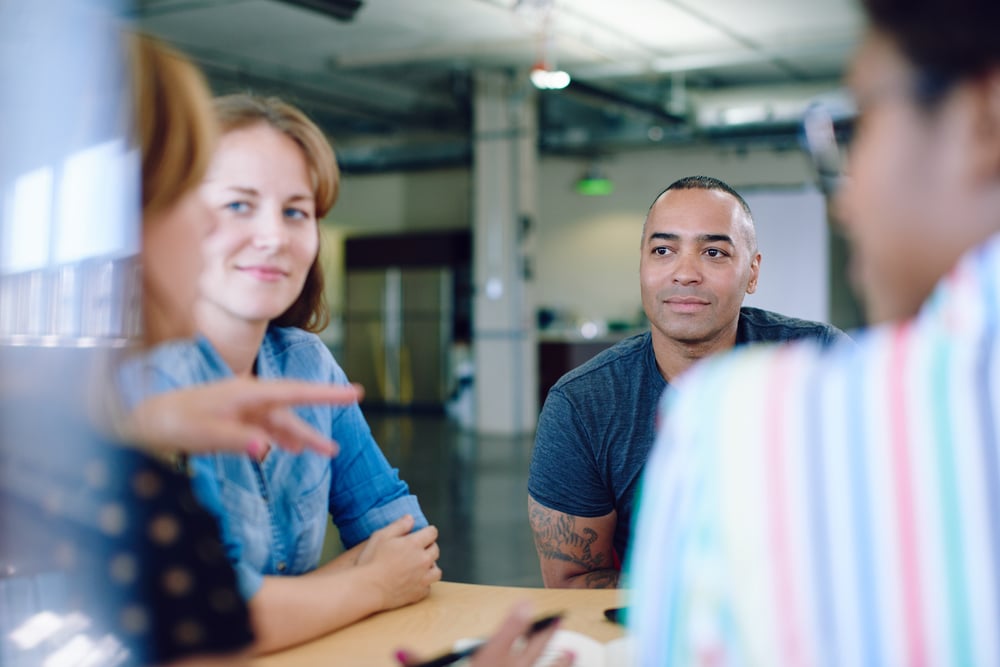 Unposed group of creative business people in an open concept office brainstorming their next project.-1